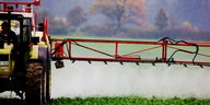 Ein Traktor versprüht weißliches Pestizid über grünen Pflanzen