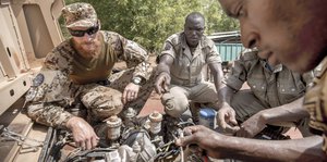 Ein Bundeswehr-Soldat hilft einem malischen Soldaten bei der Reparatur eines Autos