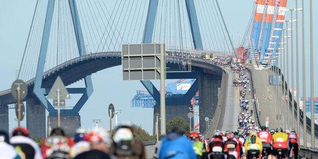 Radrennfahrer fahren die Hamburger Köhlbrandbrücke hinauf.