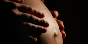 Eine hochschwangere Frau fasst sich an den Bauch