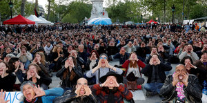 Nuit-Debout-Unterstützer sitzen auf dem Boden und halten die Hände zum Sprechtrichter geformt