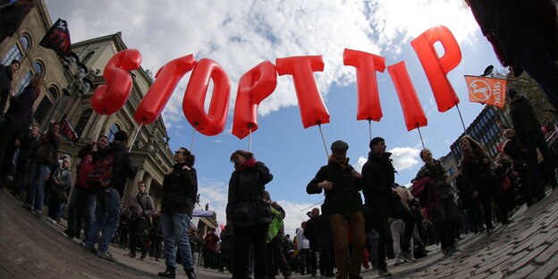 Demonstrierende Menschen tragen Buchstaben-Luftballons, die die Worte Stop TTIP bilden