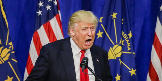 Ein Mann mit schlechter Frisur spricht in ein Mikrofon, es ist Donald Trump
