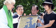 Vier Menschen halten das Portraitbild Hinzpeters in Händen