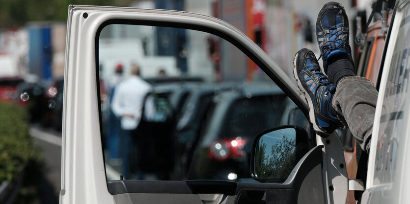 Ein Lkw-Fahrer streckt seine Füße durch die Fensterscheibe seiner offenen Fahrertür.