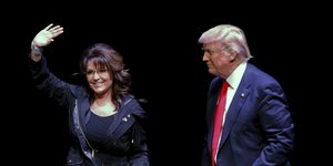 Sarah Palin (links) winkt von einer Bühne herab, rechts steht Donald Trump, der sie anblickt.