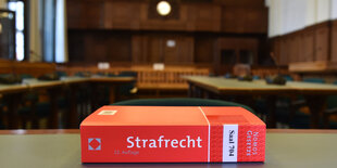 Ein Buch mit der Aufschrift "Strafrecht" liegt in einem Gerichtssaal