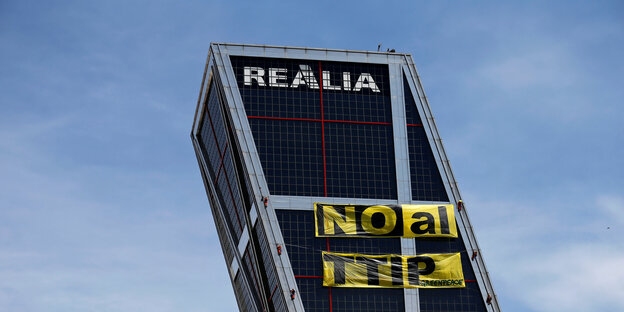 Greenpeace-Aktivisten befestigen ein gelbes Banner an der Fassade eines der Kio Towers in Madrid