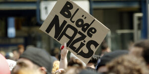 In einer Demo wird ein Plakat mit der Aufschrift „Blöde Nazis“ hochgehalten