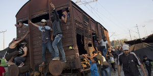 Männer schieben und stehen auf einem alten Eisenbahnwaggon