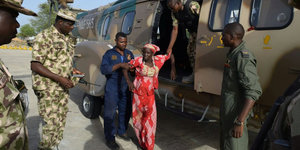Eine junge Frau, es ist Amina Ali Nkeki, steigt aus einem Helikopter, um sie herum stehen Männer