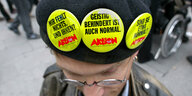 Ein Mann, der Sticker mit der Aufschrift "Geistig behindert ist auch normal" an seiner Mütze trägt