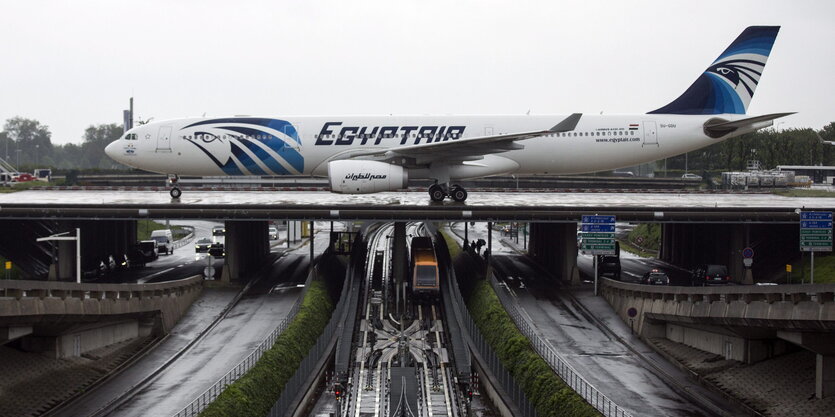 Ein Flugzeug auf einem Rollfeld, dass auf einer Brücke über Schienen und Straßen verläuft