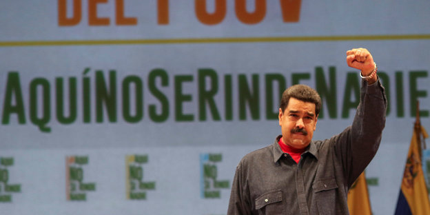 Nicolàs Maduro steht mit linker, in die Höhe gereckter Faust auf einer Bühne