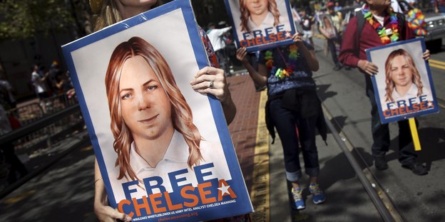 Menschen tragen "Chelsea-Free"-Plakate durch eine Straße