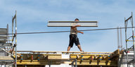 Ein Arbeiter trägt eine Stahlstange über eine Haus-Baustelle in Dresden
