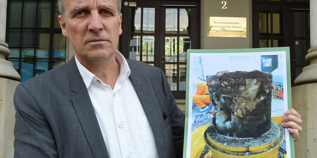 Niedersachsens Umweltminister Stafan Wenzel hält eine Foto mit dem deffektem Atommüllfass hoch