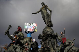 Menschen mit einem Plakat auf einer Statue