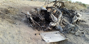 Ein zerstörtes Auto in einer Sand-Landschaft