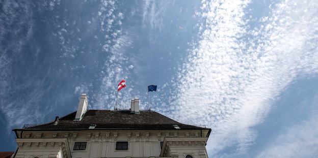 ein Dach mit zwei Flaggen vor blauem Himmel