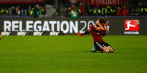 ein kniender Spieler mit hinter dem Kopf verschränkten Armen auf dem Rasen, im Hintergrund der Schriftzug „Relegation 2016“