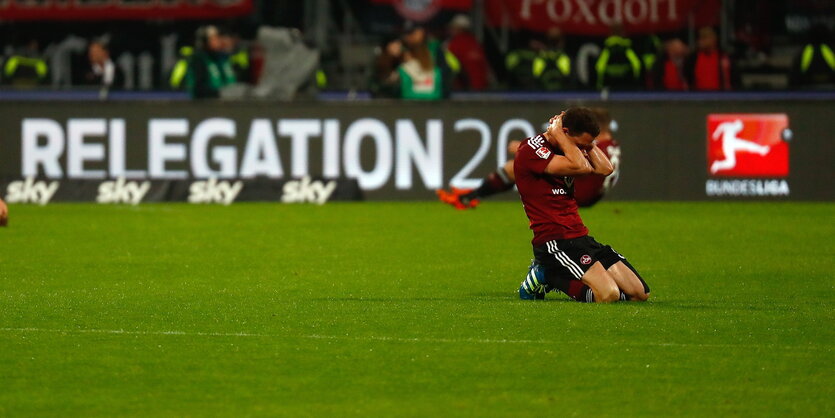 ein kniender Spieler mit hinter dem Kopf verschränkten Armen auf dem Rasen, im Hintergrund der Schriftzug „Relegation 2016“