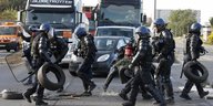 Polizisten in schweren Schutzuniformen tragen Autoreifen weg