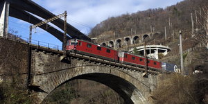 ein roter Zug überquert eine alte Brücke
