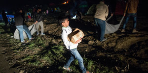Ein Junge mit Brennholz in einem Flüchtlingslager