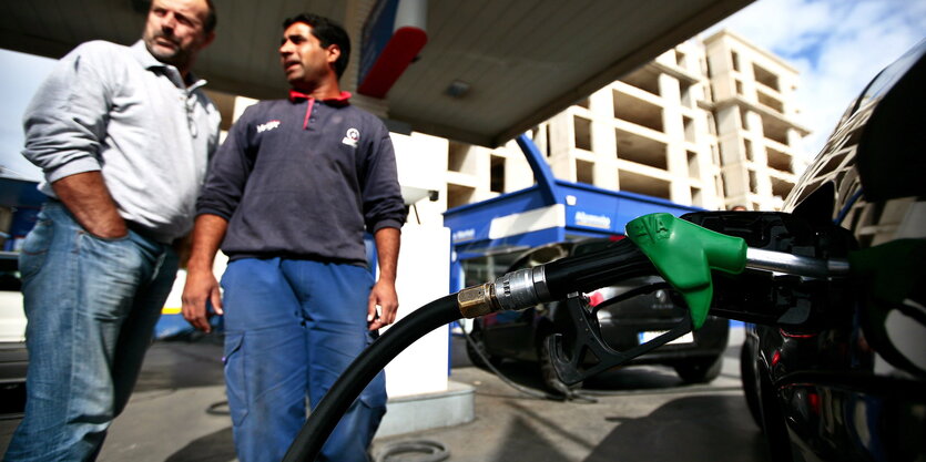 Zwei Männer stehen an einer Tankstelle