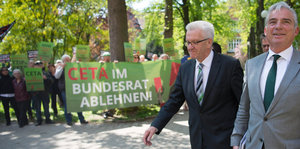 Winfried Kretschmann und Thomas Strobl laufen an einem Anit-Ceta-Protest vorbei