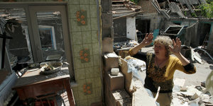 Eine Frau steht vor den Trümmern ihres Hauses in Staromikhailovka