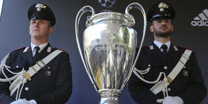 Zwei Männer in Uniform stehen hinter einem Pokal