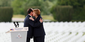 Angela Merkel und François Hollande umarmen sich vor vielen Reihen weißer Kreuze auf einem Soldatenfriedhof