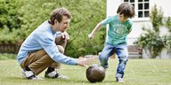 Vater und Sohn spielen im Garten Fußball