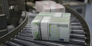 Bündel von 100-Euro-Scheinen auf einem Fließband