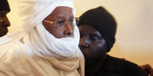 Tschads Exdiktator Hissène Habré steht in einem weißen Gewand und Kopftuch im Gerichtssaal, 2015