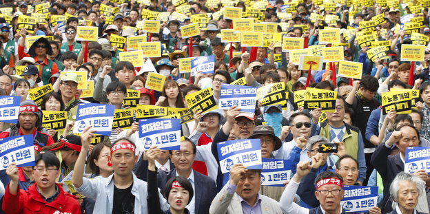 Gewerkschafter in Seoul halten gelbe Schilder in die Luft