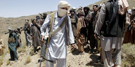 Bewaffnete Taliban-Kämpfer auf dem Fußmarsch durch eine hügelige Landschaft