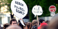 Menschen halten Schilder gegen Polizeigewalt hoch