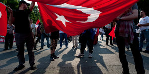 Menschen halten eine riesige Flagge der Türkei