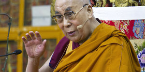 Ein Mann mit Brille und gelbem Gewand. Es ist der Dalai Lama
