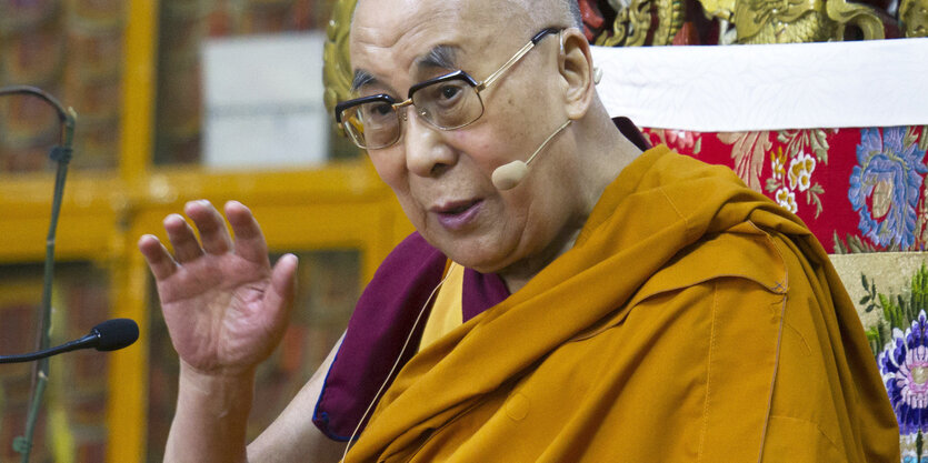 Ein Mann mit Brille und gelbem Gewand. Es ist der Dalai Lama