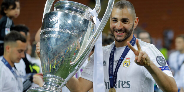 Karim Benzema nimmt lächelnd einen großen silbernen Pokal entgegen