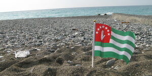 Eine Fahne steckt im Strandsand
