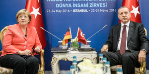 Zwei Menschen sitzen vor Türkeiflaggen
