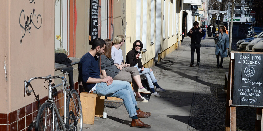 Menschen sitzen vor einem Laden