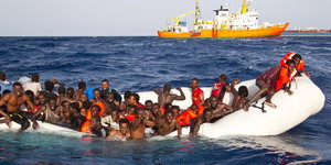 Ein sinkendes Schlauchboot mit Flüchtlingen im Mittelmeer
