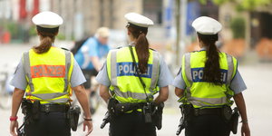 Drei Polizistinnen in Warnwesten von hinten