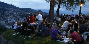 Menschen picknicken unter Bäumen mit Blick auf Sarajevo